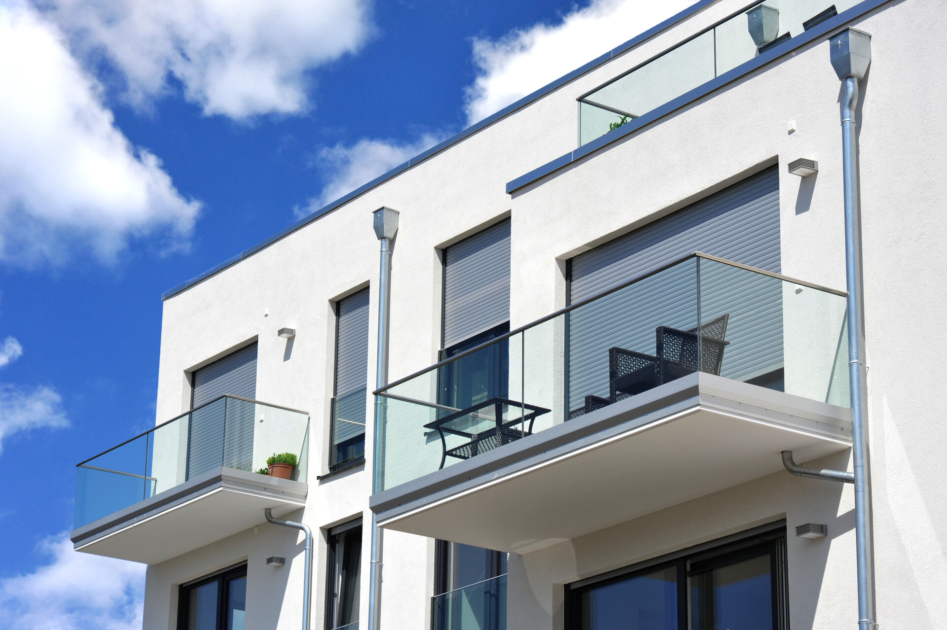 Moderne Balkone mit Rolläden, verglast mit Metall-Geländer an Neubau-Hausfront