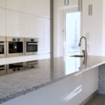 Moderne Küche mit Granitarbeitsplatte, Einbaugeräten und Induktionskochfeld